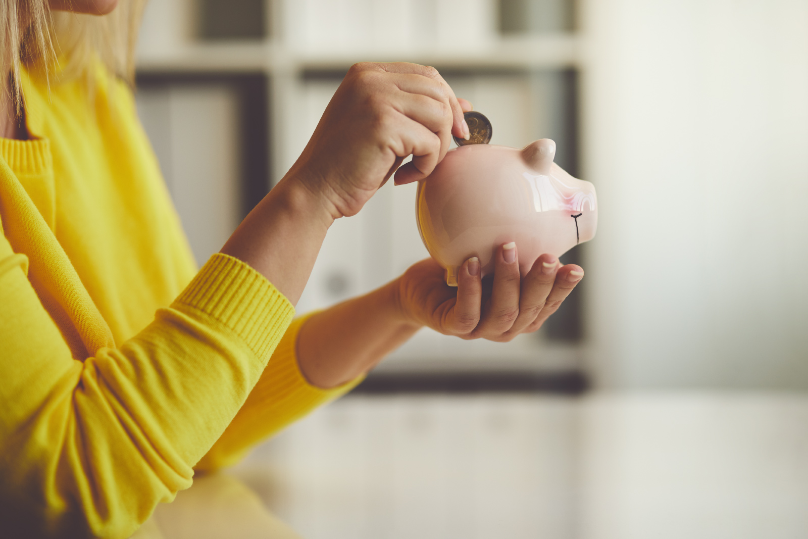 Consumer inserting coins into a piggy bank.